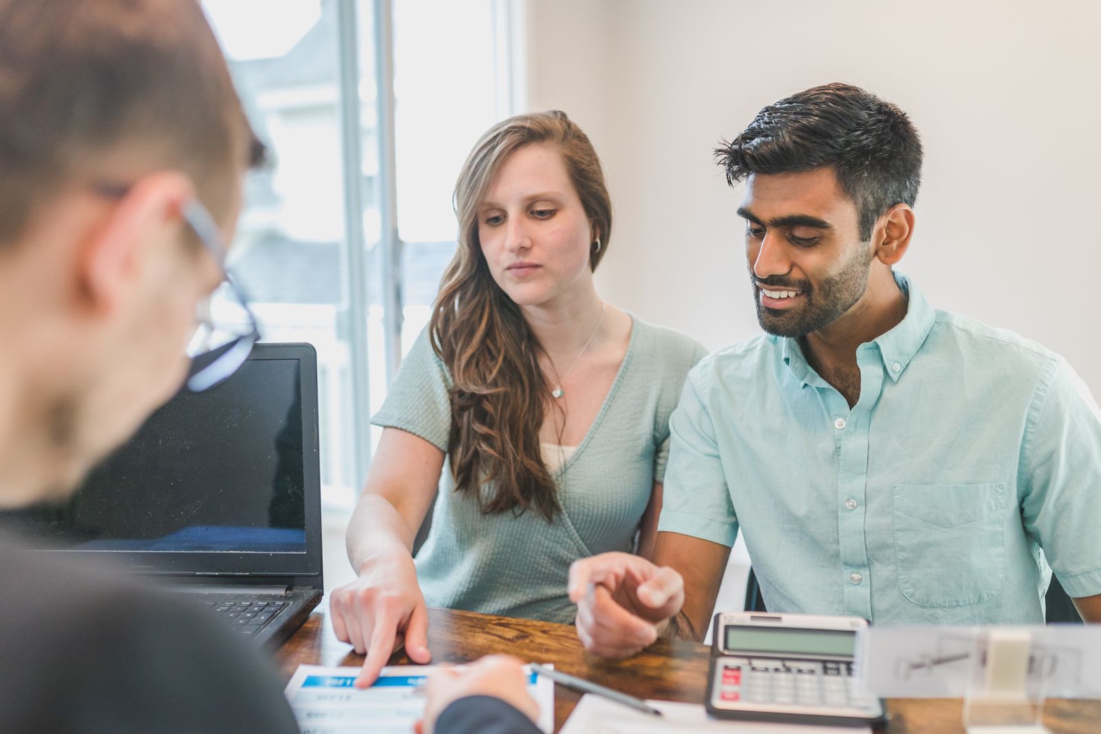 Two people reviewing financial documents with a calculator